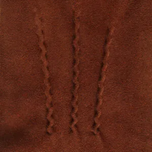 Close-up van drie klassieke sierstiksels en de fijne bruin suede leerstructuur